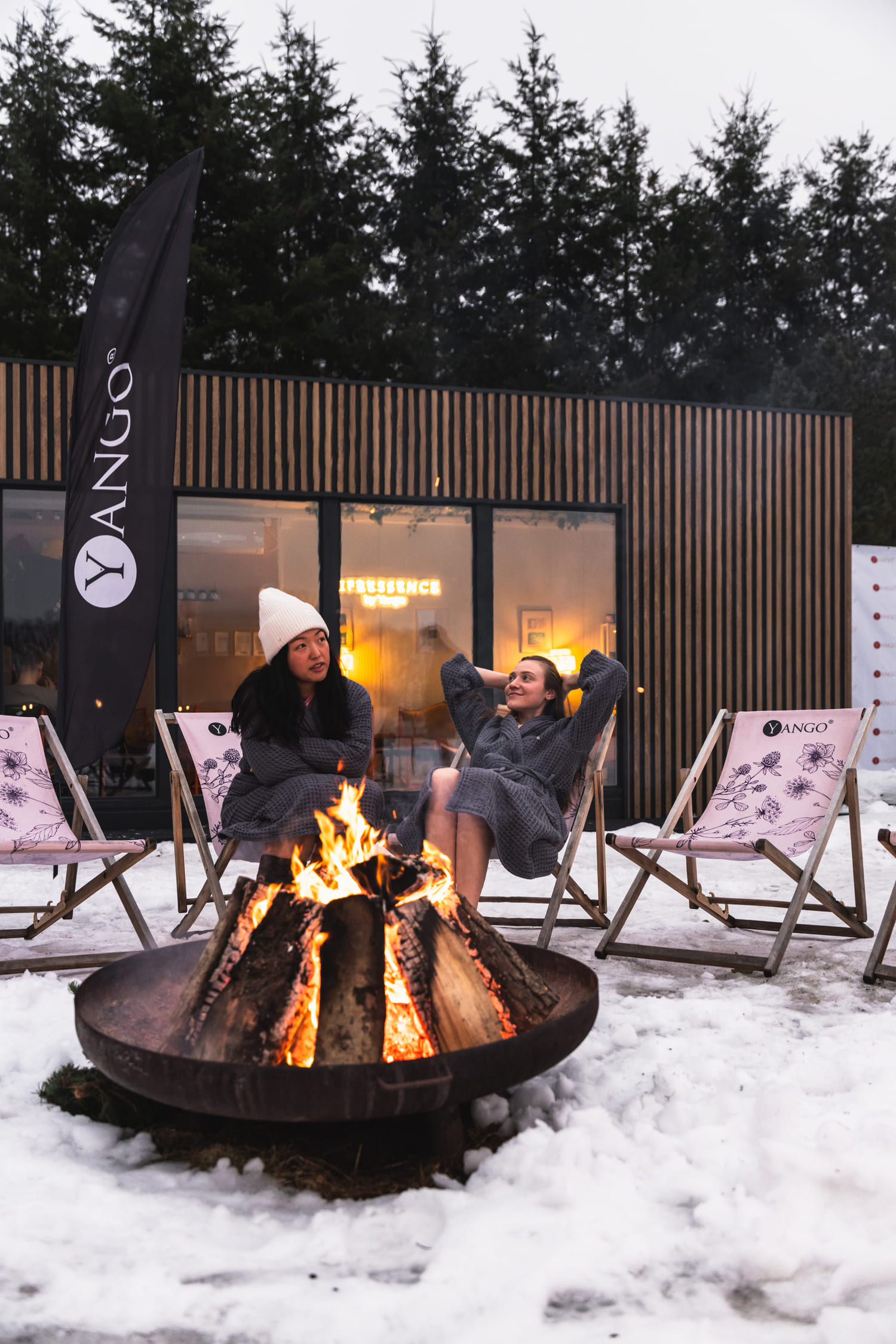 Dwie kobiety siedzące na leżakach przy ognisku